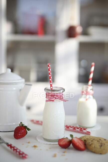 Bottles of milk and strawberries cookies — Stock Photo