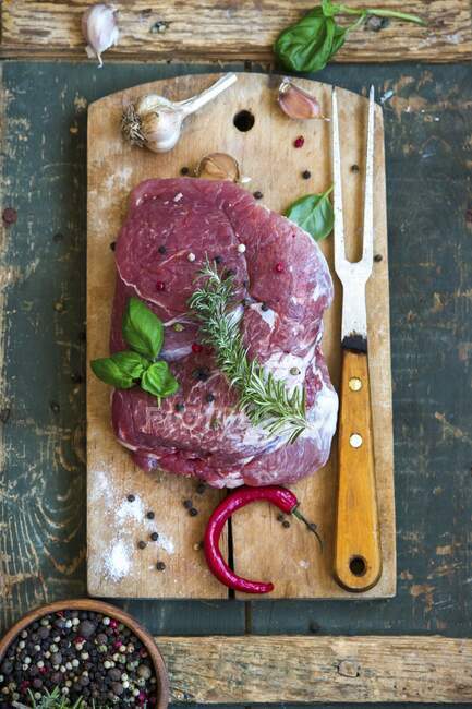 Raw pork with herbs, garlic, pepper and chilli on a chopping board — Stock Photo