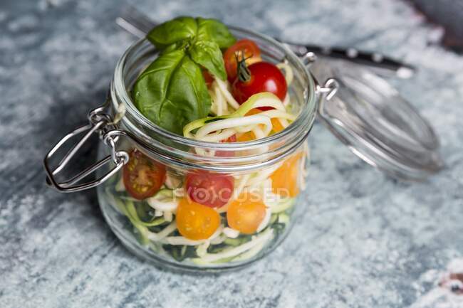 Nouilles (nouilles aux courgettes) dans un bocal en verre avec tomates et basilic — Photo de stock