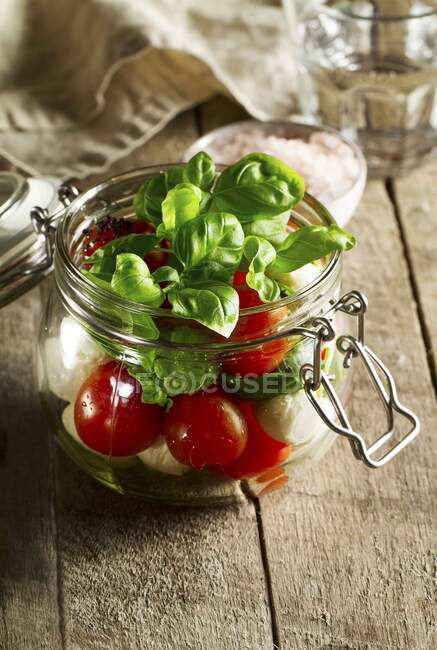 Tomatoes, mozzarella and basil in a glass jar — Stock Photo