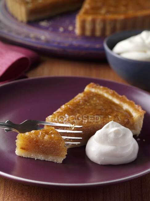 A slice of treacle tart on a plate with the whole tart behind — Stock Photo