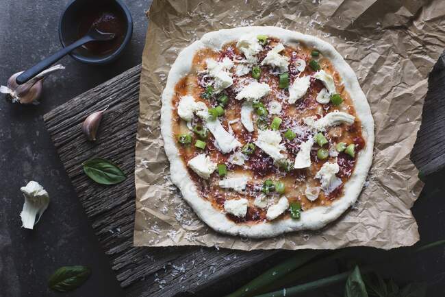 Pizza casera sin cocer con tomate, bocconcini y albahaca - foto de stock