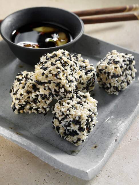 Deep fried tofu coated in black and white sesame seeds dipping sauce — Stock Photo