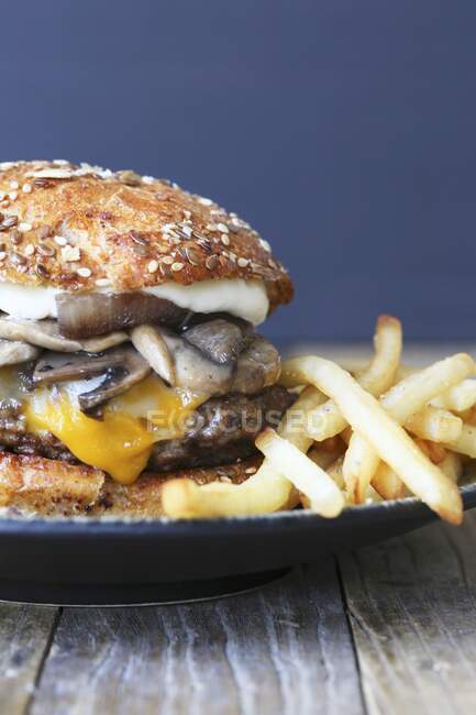 Hambúrguer de queijo com cogumelos e batatas fritas — Fotografia de Stock