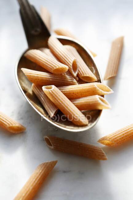 Uncooked red penne rigate on a spoon — Stock Photo