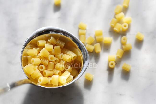 Uncooked ditalini rigate in and next to a ladle — Stock Photo