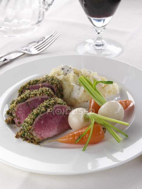 Un piatto di lombo di agnello in una crosta di erbe con verdure — Foto stock