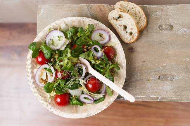 Salada de vegan (trigo einkorn, tomates, alface de cordeiro, anéis de cebola vermelha, alface iceberg, agrião, pimenta) em uma tigela de folha de palmeira — Fotografia de Stock