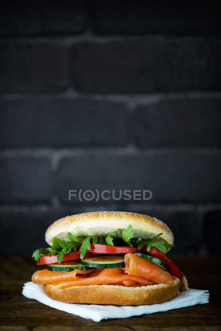Um bagel com salmão defumado, pepino, tomate e foguete — Fotografia de Stock