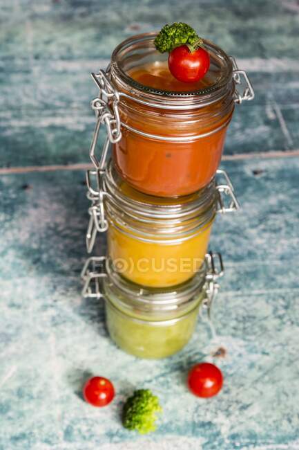 Varias sopas de colores en frascos de vidrio, sopa de brócoli, sopa de tomate, sopa de calabaza - foto de stock