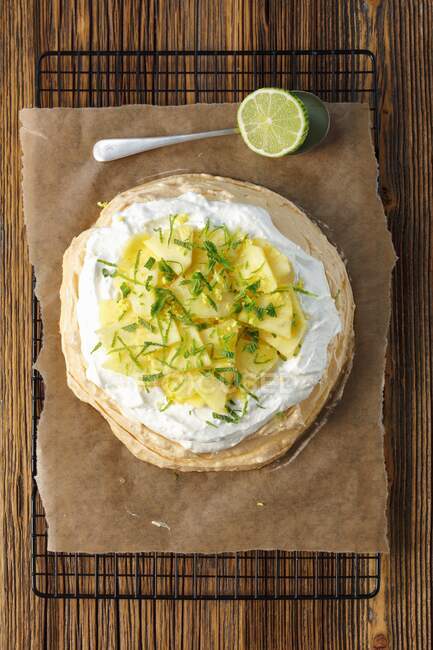 Meringue cake with coconut cream, pineapple slices and lime zest — Stock Photo