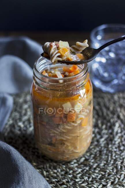 Pasta soup with prosciutto and vegetables in a glass jar — Stock Photo