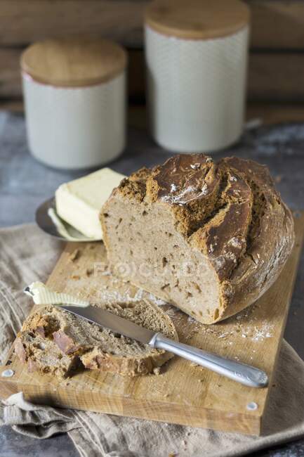 Homemade beer bread baked in a clay pot with butter on a wooden board — Stock Photo
