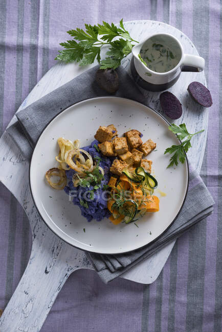 Vegan purple mashed potatoes with zucchini-carrot-vegetables and tofu — Stock Photo