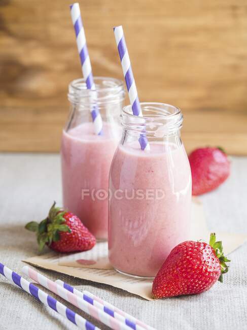 Strawberry smoothies in glass bottles with drinking straws — Stock Photo