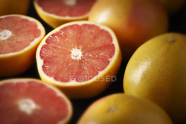 Грейпфруты, цельные и наполовину, крупным планом — стоковое фото