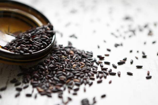Black rice tipped out of a small bowl — Stock Photo