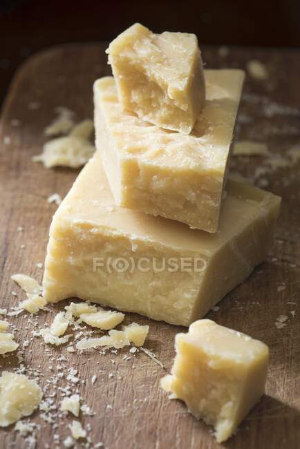 Chunks of parmesan cheese arranged on top of each other on wooden board — Stock Photo