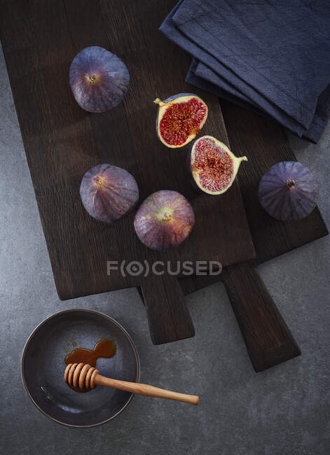 Figos frescos em uma placa de corte escura com um conta-gotas de mel — Fotografia de Stock