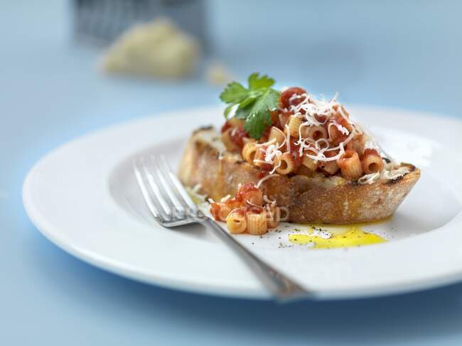 Pasta with tomato sauce and grated cheese on grilled bread — Stock Photo