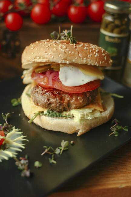 Una hamburguesa con tomate y un huevo frito - foto de stock