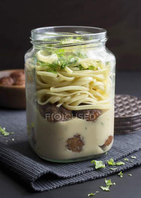 Meatballs and tagliatelle in a glass jar with soy cream and fresh parsley — Stock Photo