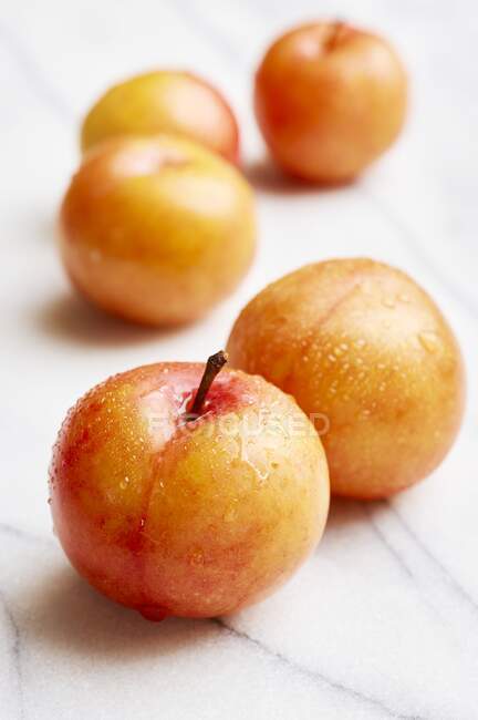 Yellow plums on a white marble plate — Stock Photo