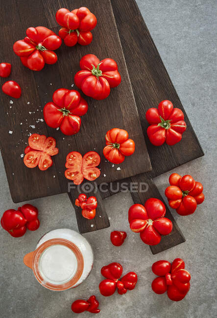 Tomatoes on a dark cutting board with coarse sea salt — Stock Photo