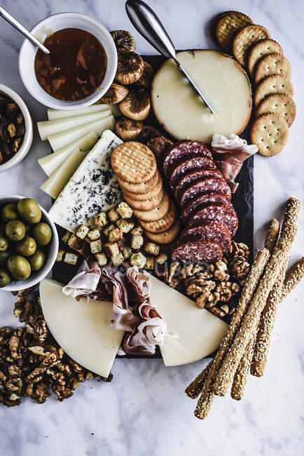Cheese and salami board with crackers and olives — Stock Photo