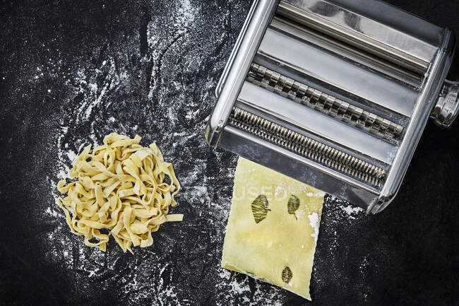 Homemade ribbon noodles and lasagne sheets with sage and a pasta machine — Stock Photo
