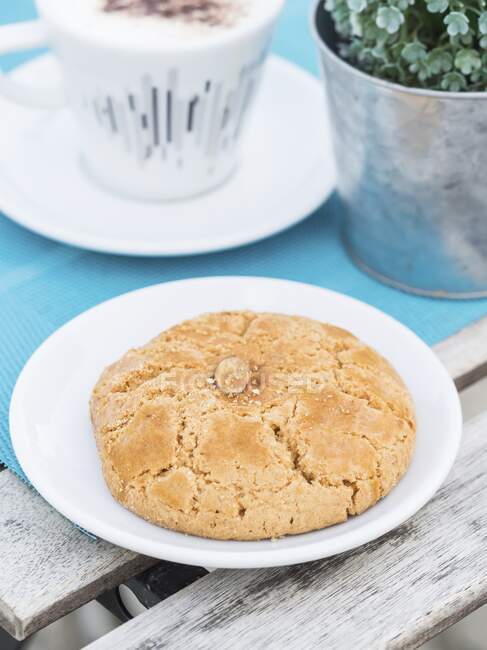 Um biscoito de amêndoa português numa mesa com uma chávena de café — Fotografia de Stock