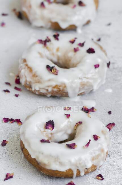 Três donuts polvilhados com pétalas de rosa secas — Fotografia de Stock