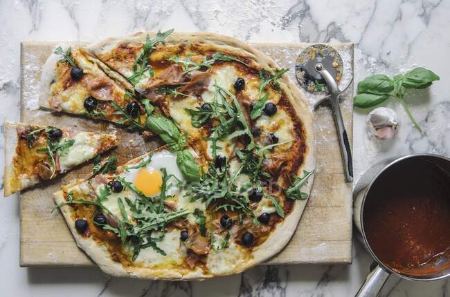 Pizza with tomato sauce, fried egg, rocket, olives and parmesan — Stock Photo