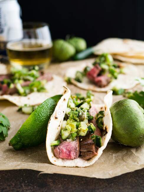 Tacos with flank steak, Pico de Gallo Verde, limes and tomatoes — Stock Photo