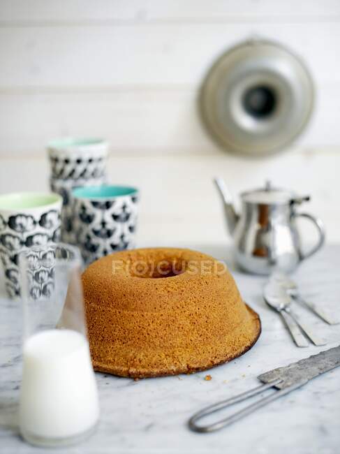 A sponge cake with a jug of milk — Stock Photo