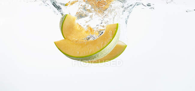 Melón de melón cayendo en agua dulce - foto de stock