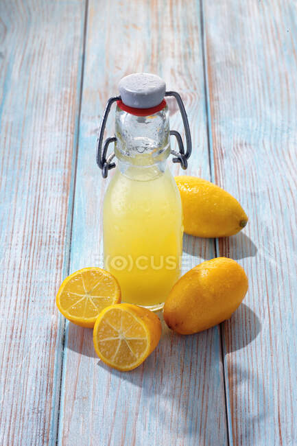 Suco de kumquat fresco em garrafa cercado com frutas inteiras — Fotografia de Stock