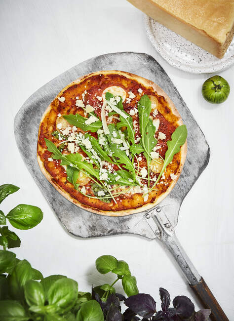 Pizza with arugula and parmesan on a pizza shovel — Stock Photo