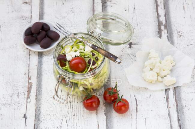 Nouilles (nouilles aux courgettes) dans un bocal en verre aux tomates, feta et olives — Photo de stock