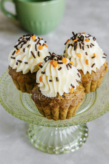 Cupcakes de zanahoria y nueces especiadas, decorados con glaseado de queso crema y espolvoreos - foto de stock