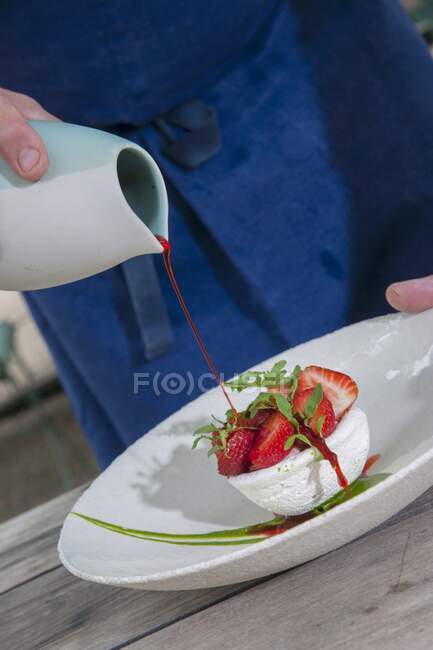 A meringue nest with strawberries, rocket, and strawberry sauce — Stock Photo