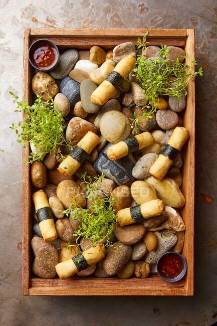 Spring rolls served on a wooden tray with stones (Asia) — Stock Photo