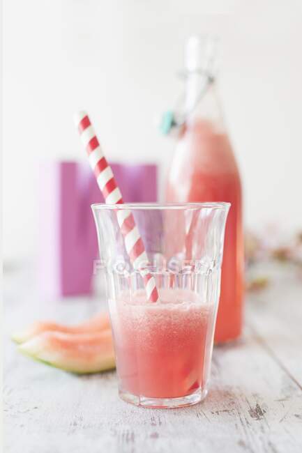 Half of glass of Watermelon lemonade with striped straw — Stock Photo