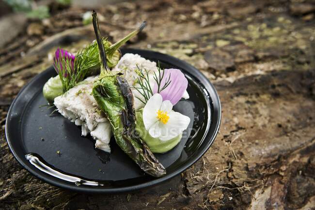 Fish fillet with grilled chilies served with flowers on camping plate — Stock Photo