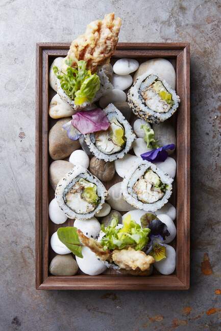 California rolls served on a wooden tray with stones (Japan) — Stock Photo