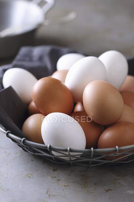 Коричневі та білі курячі яйця у дротяному кошику. — стокове фото