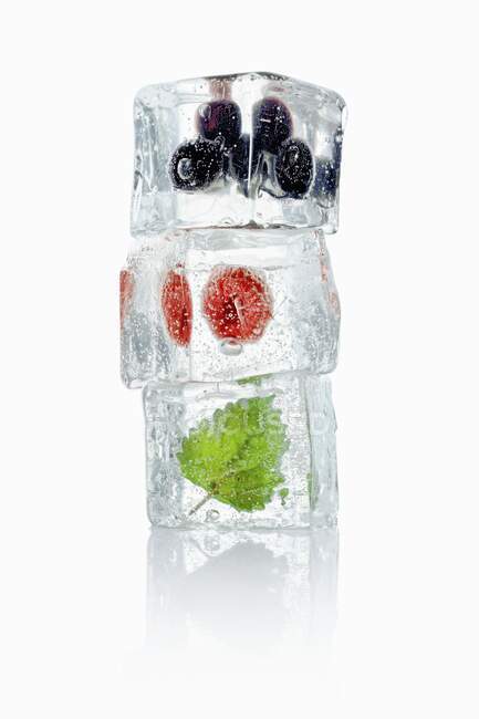 Ice cubes with blueberries, raspberries and mint leaves — Stock Photo