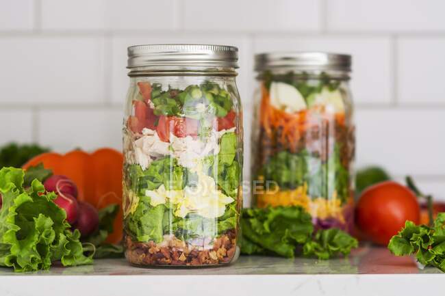 Salades en deux couches dans des bocaux en verre aux épinards, haricots, fromage et œufs — Photo de stock