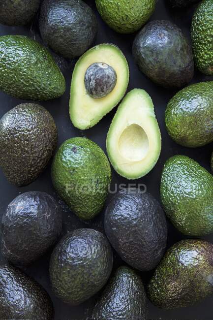 Ripe avocado on a black wooden surface — Stock Photo