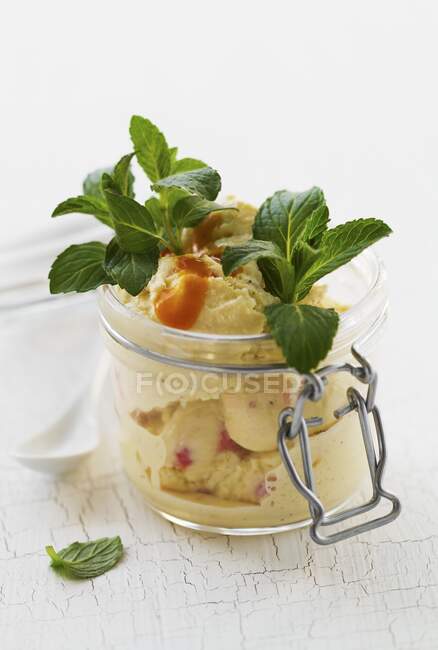 Vanille- und Erdbeereis mit Fruchtsauce und Minze im Einmachglas — Stockfoto